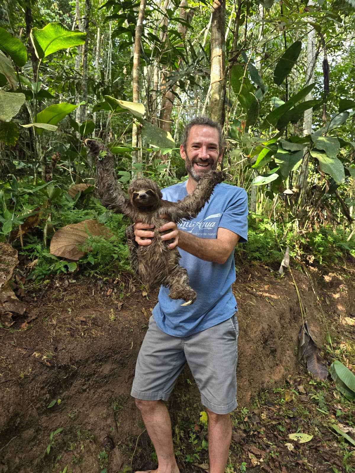 Wade holding a baby sloth in the rainforest near Dreamglade